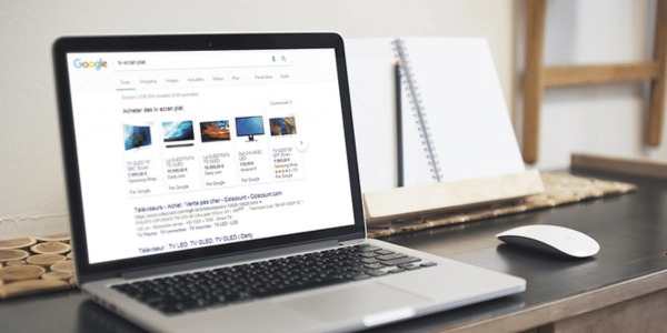 A laptop on a desk displaying Google Shopping search results with product listings and prices representing the setup and management of Google Shopping campaigns for ecommerce businesses