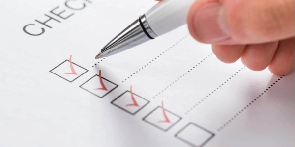 A hand checking off items on a paper checklist representing the step-by-step process of a Google Ads account audit