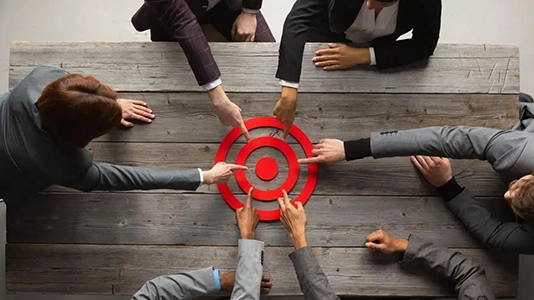 Team of professionals reaching toward a shared target, representing the combined use of remarketing and retargeting strategies