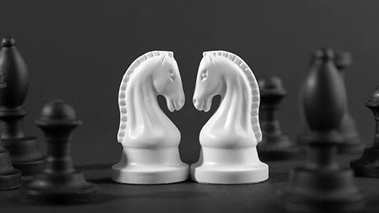 Two white chess knights facing each other on a dark board, representing competition between businesses in paid search